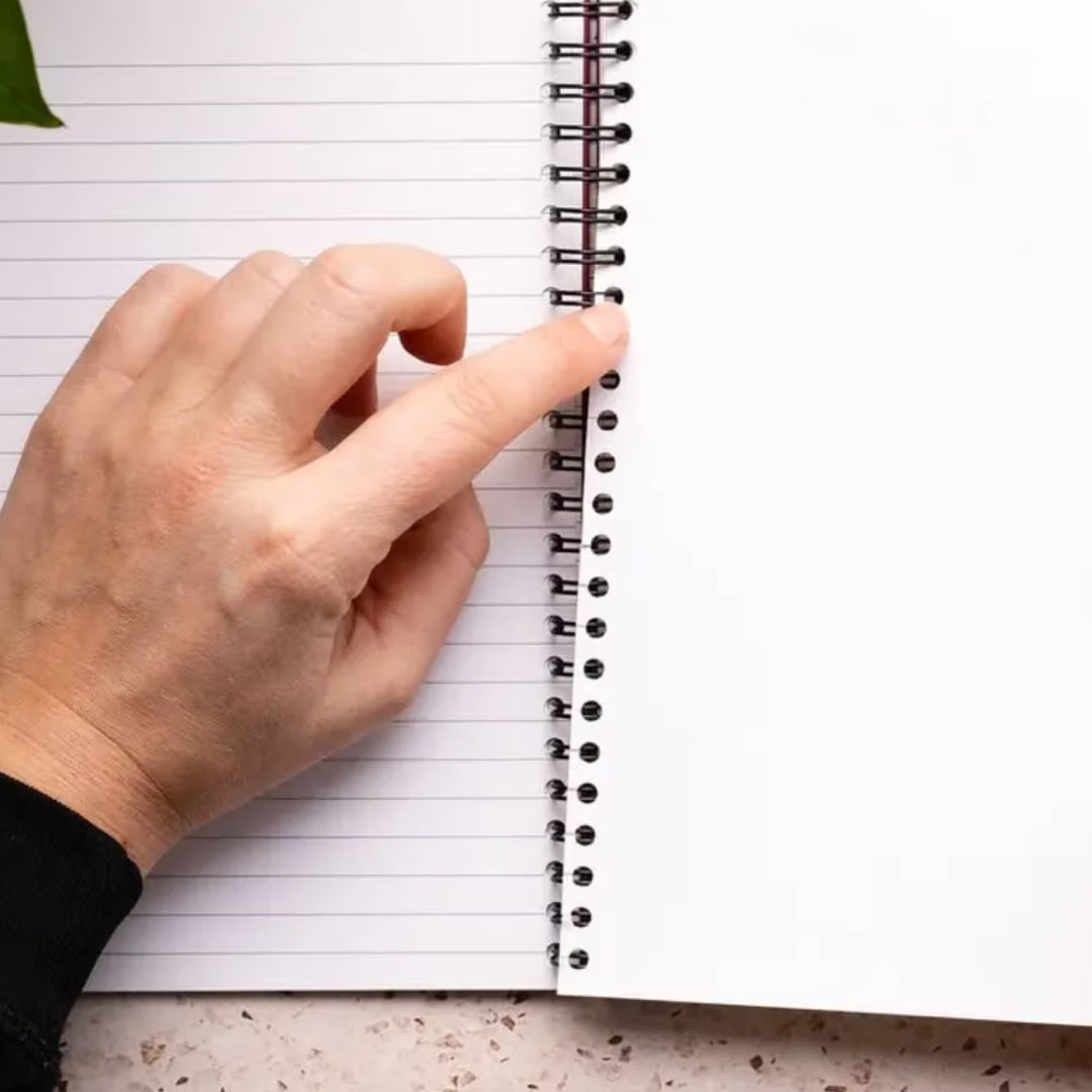 Hand holding a spiral-bound notebook with lined pages on a white background
