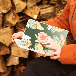 Woman holding a Soul Compass notebook in the woods